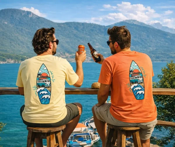 deux homme en t-shirts van life assis face à un lac de montagne entrain de faire l'apéritif