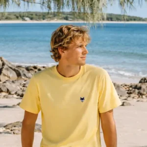 Homme portant un t-shirt vanlife jaune en bord de mer – esprit été