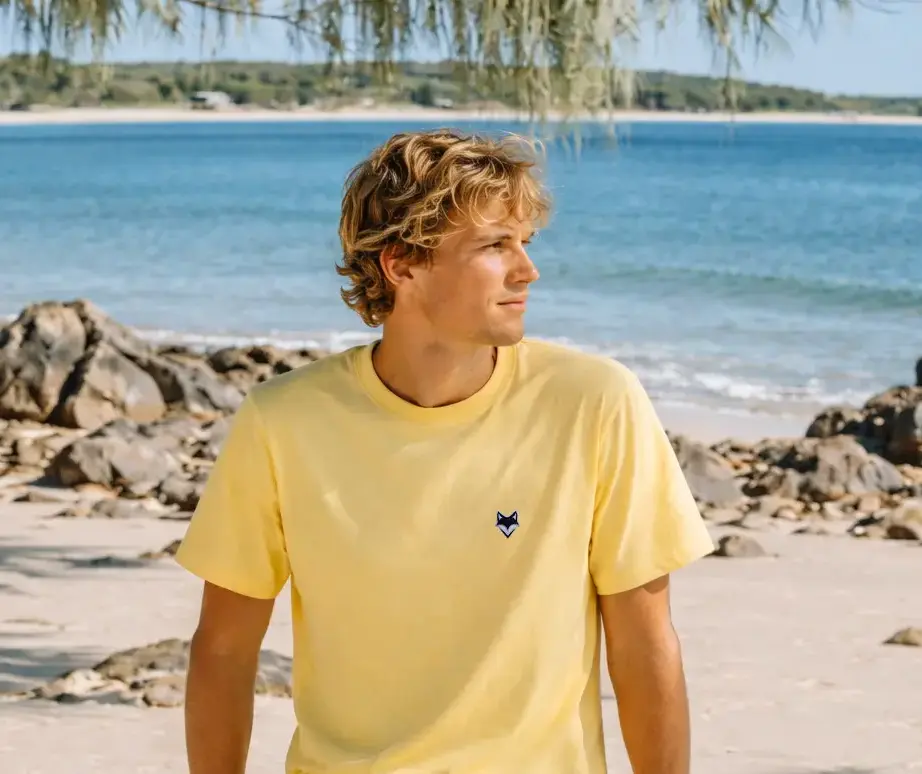 Homme portant un t-shirt vanlife jaune en bord de mer – esprit été