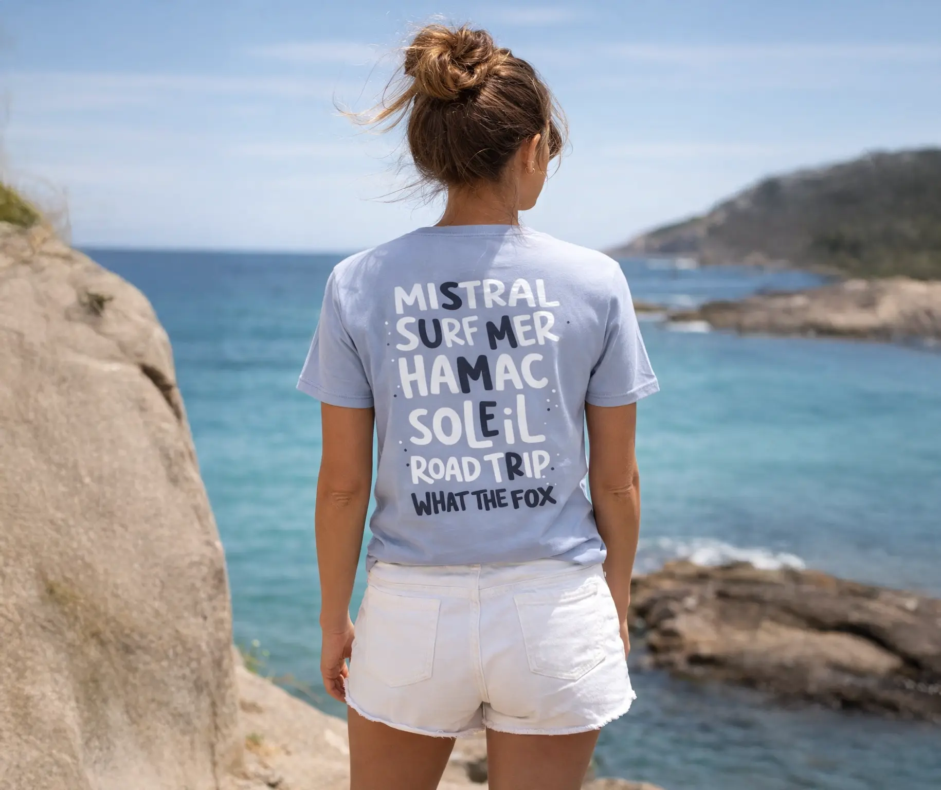 Femme de dos portant un t-shirt en coton bio de couleur lila devant la mer méditerrannée dans le sud de la france lors d'une randonnée