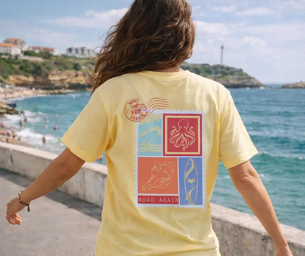 femme de dos portant un tee shirt bio le tee shirt est jaune ananas le visuel retro fait penser à un timbre avec des motif surfeur / van life